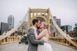 Bride and groom sharing a kiss on Pittsburgh's Roberto Clemente Bridge on their wedding day.