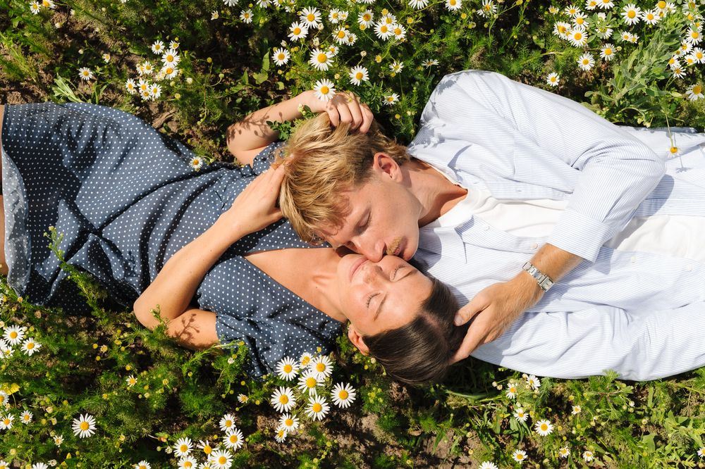 Couple relaxing among yellow flowers in a garden setting.