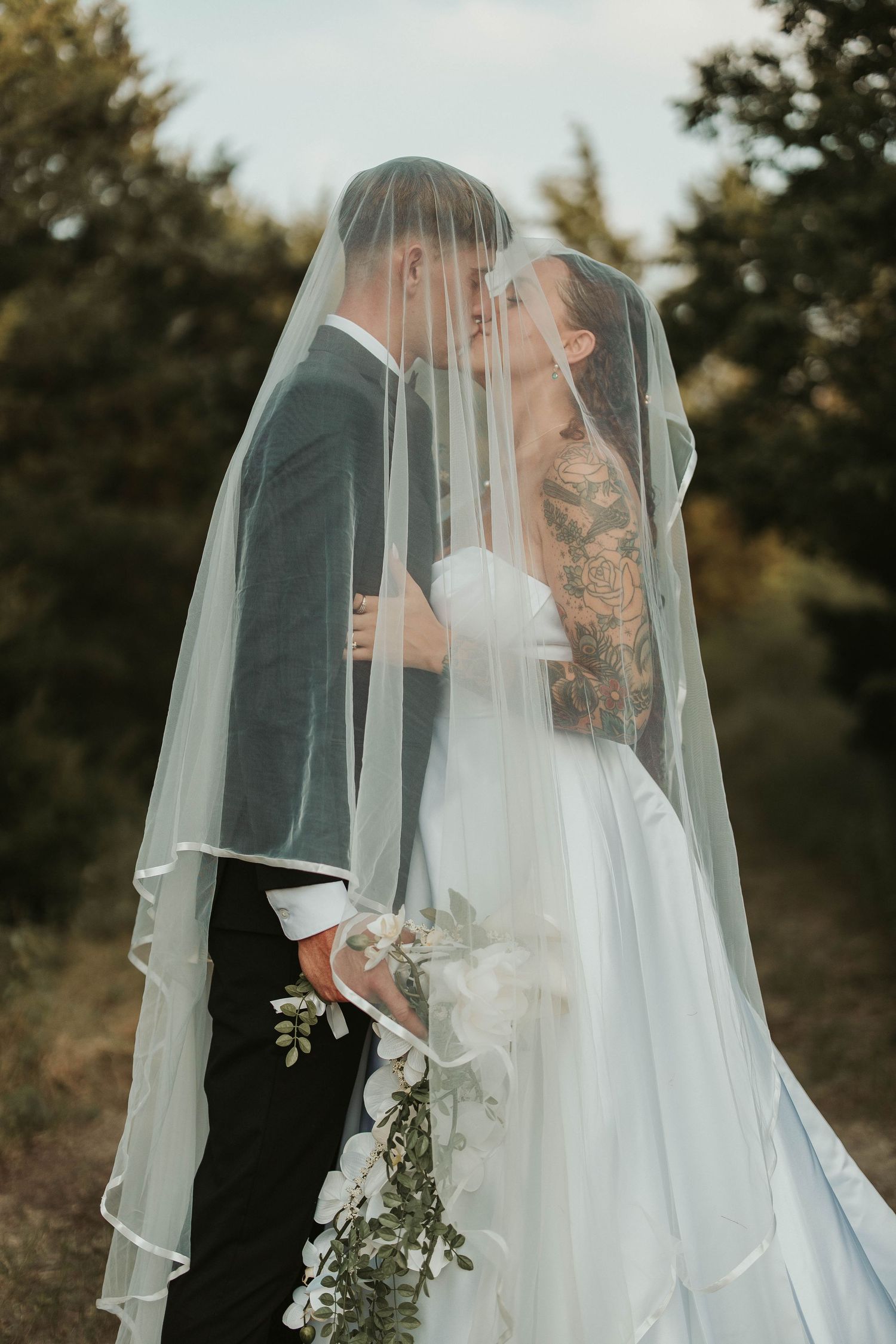 Romantic wedding photo series captured in soft, natural light on grassy field.