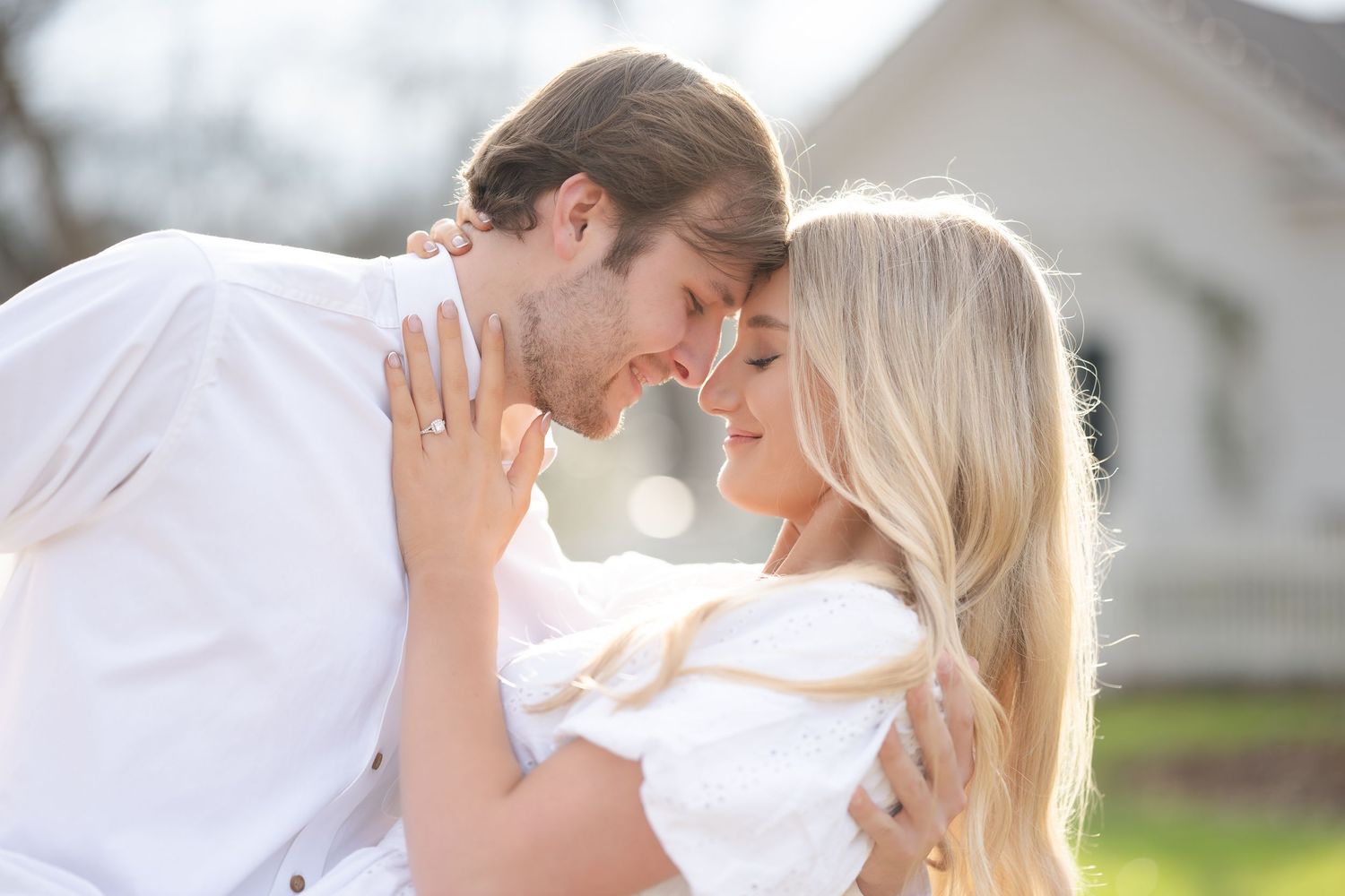 A romantic couple embraces closely while posing for a portrait in an outdoor park setting.
