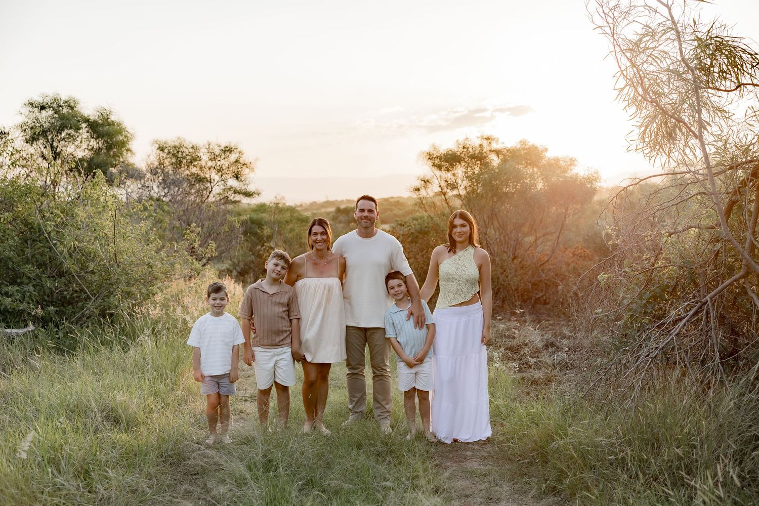 A joyful family moment captured at sunset on a rocky beach.
