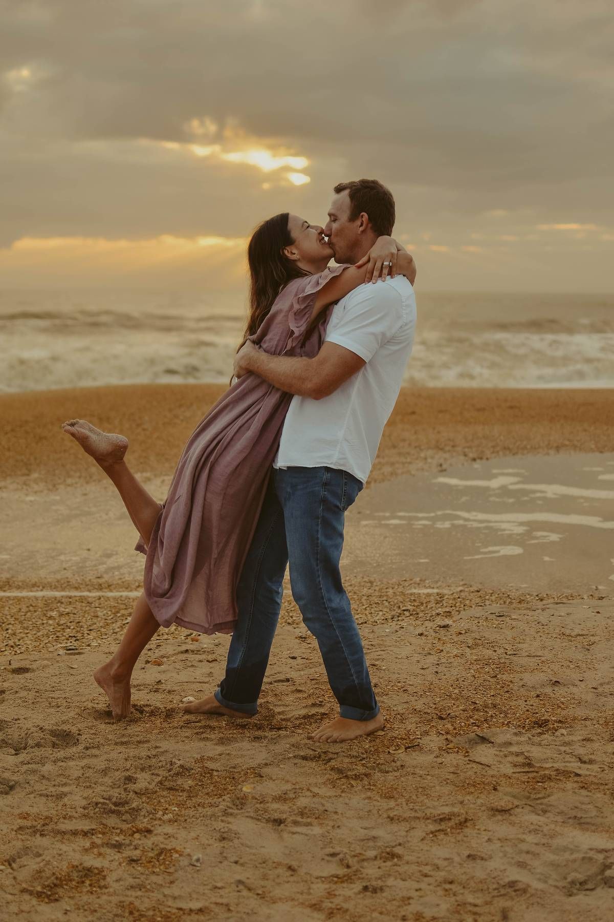Couple shares intimate dance moves on sandy beach at sunset.