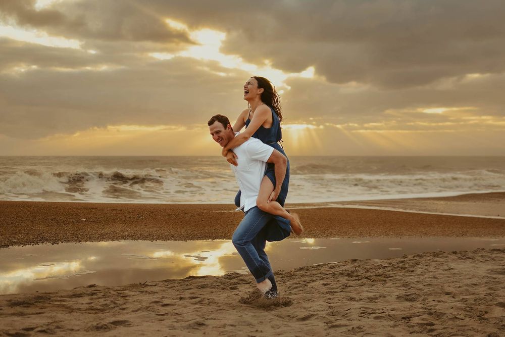 Romantic beach photoshoot with couple dancing in golden sunset light.