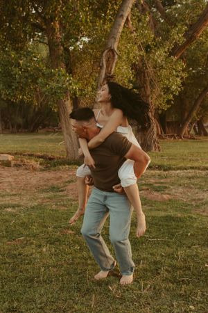 A playful couple dancing in a sun-dappled grove during golden hour.