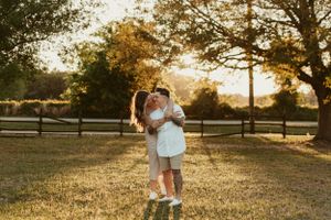 Family plays together in golden sunlit field during sunset photo session.