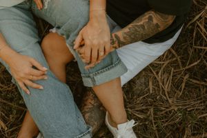 Close-up details of casual denim and tattoos in outdoor setting.