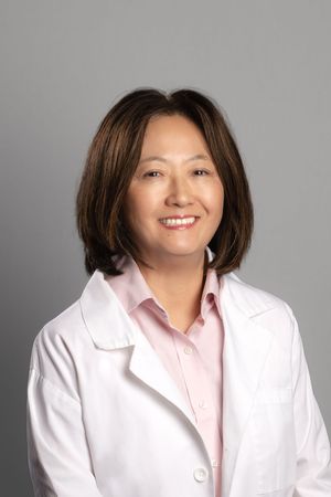 A series of professional headshots showing someone in a white lab coat and pink shirt against a gray background.