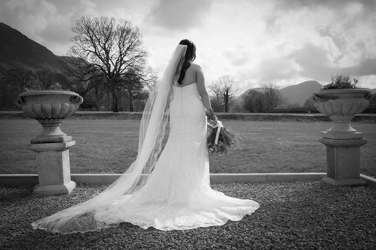 Black and white photo of a bride in a flowing gown looking down the Lorton valley at New House Farm wedding celebration