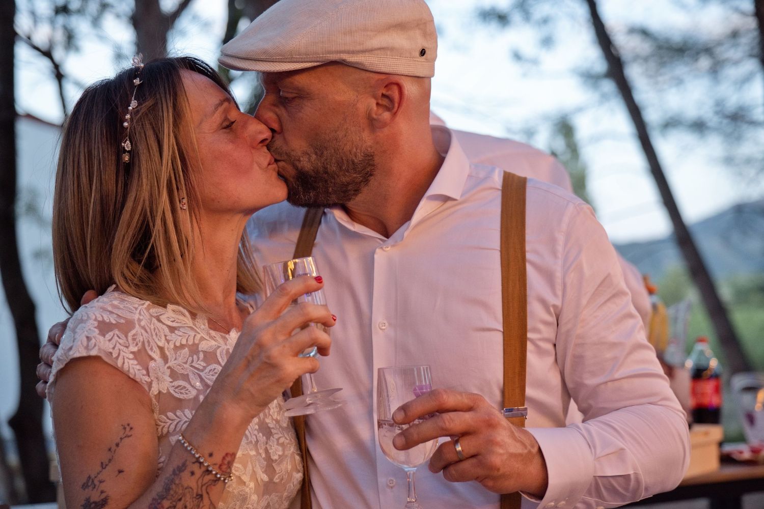 Delphine et Christophe échangent un baiser, un verre à la main, pendant leur réception au Domaine Vitòri.
