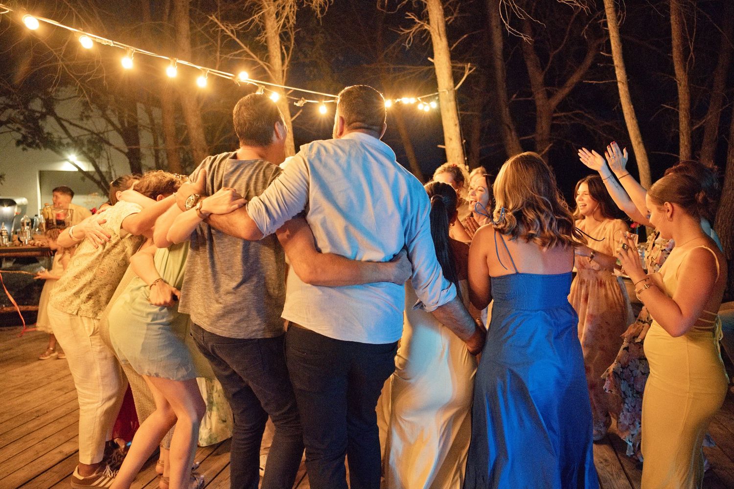 Les proches des mariés se rassemblent bras dessus bras dessous pendant la soirée en plein air.