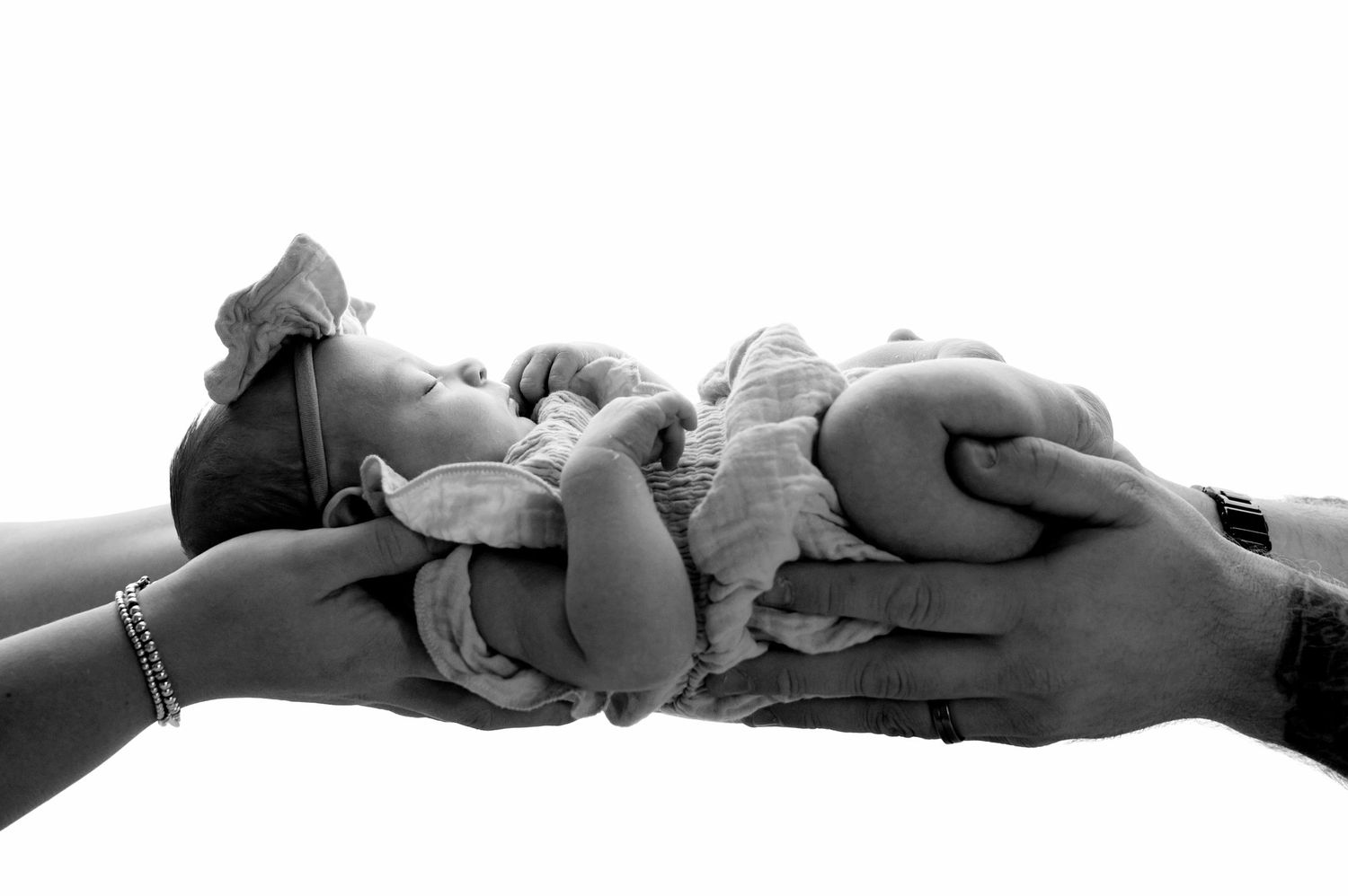 Black and white photo of a pregnant woman sitting with her toddler child, both smiling in a studio setting.