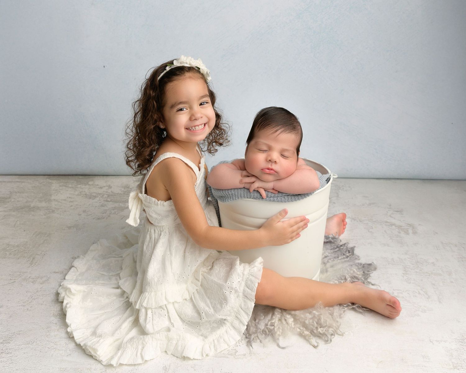 Older sister sitting safely beside her newborn sibling during a newborn photography session in Zephyrhills, Florida