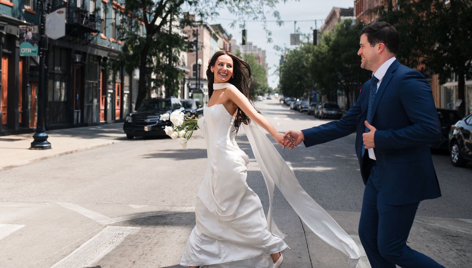 Bride and groom walking hand in hand through Over-the-Rhine in Cincinnati on their wedding day.