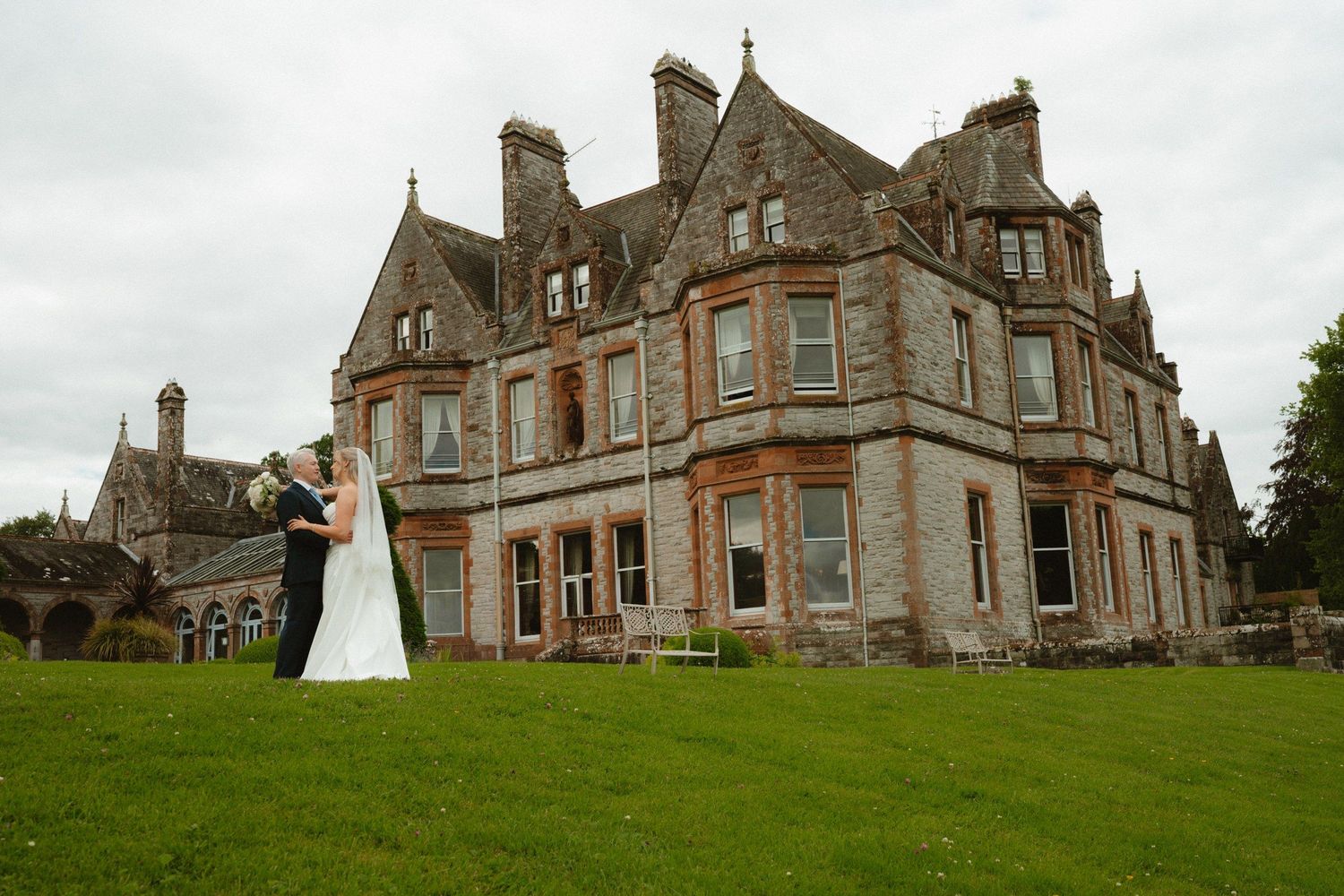 Bride and groom beside the historic castle facade at Castle Leslie Estate.