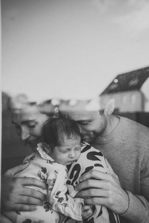 Intimate black and white photograph capturing a gentle moment with an infant.