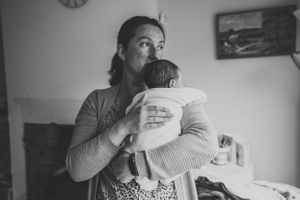Tender black and white portrait of parent holding sleeping infant.