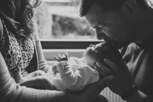 Intimate black and white moment with newborn baby and parents.