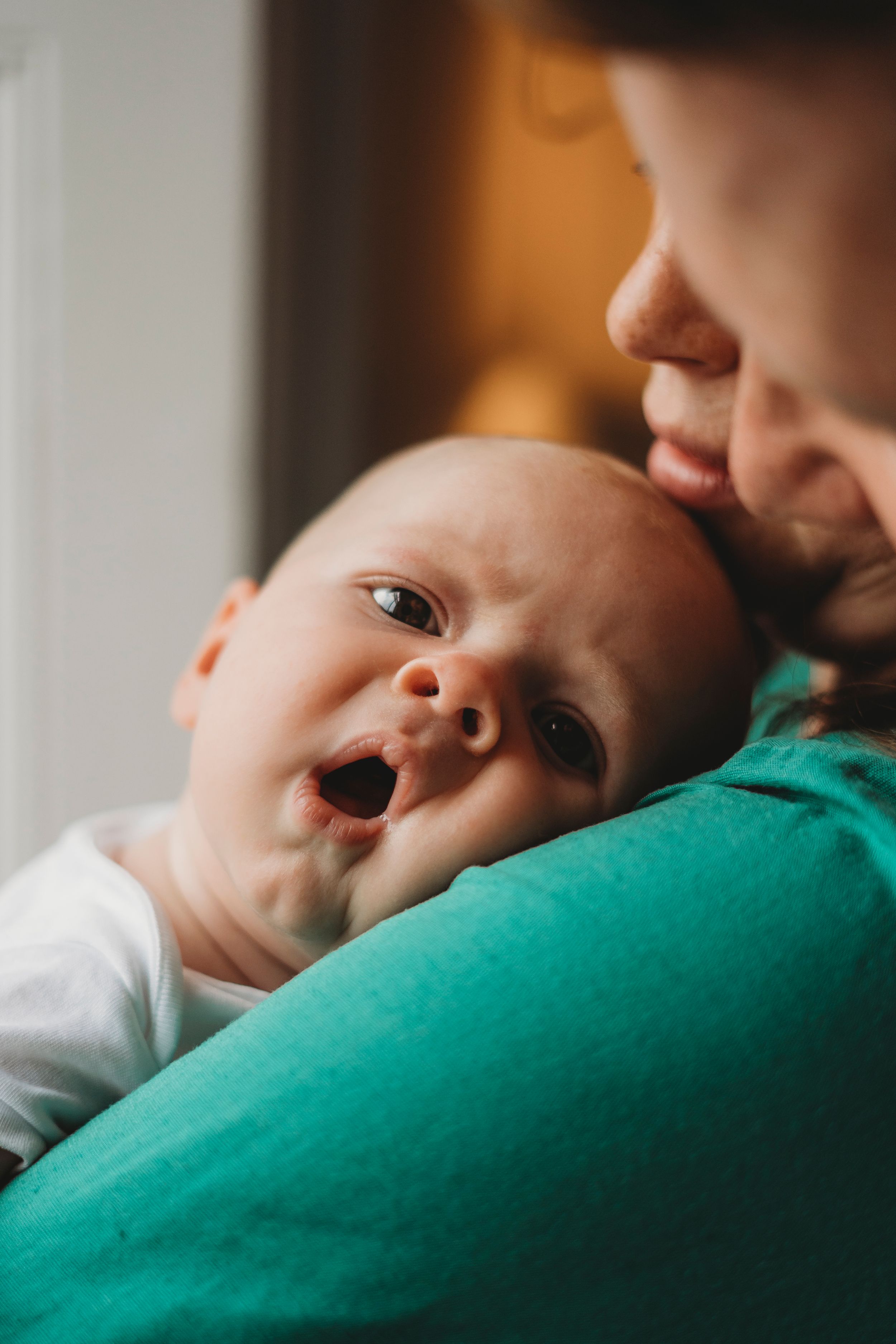 Baby smiling while being held against green fabric.