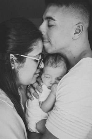 Intimate black and white family moment with sleeping newborn.