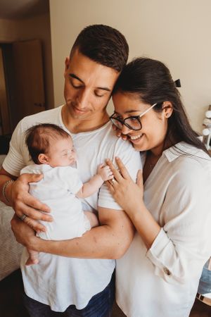 New parents share joyful moment with sleeping newborn.