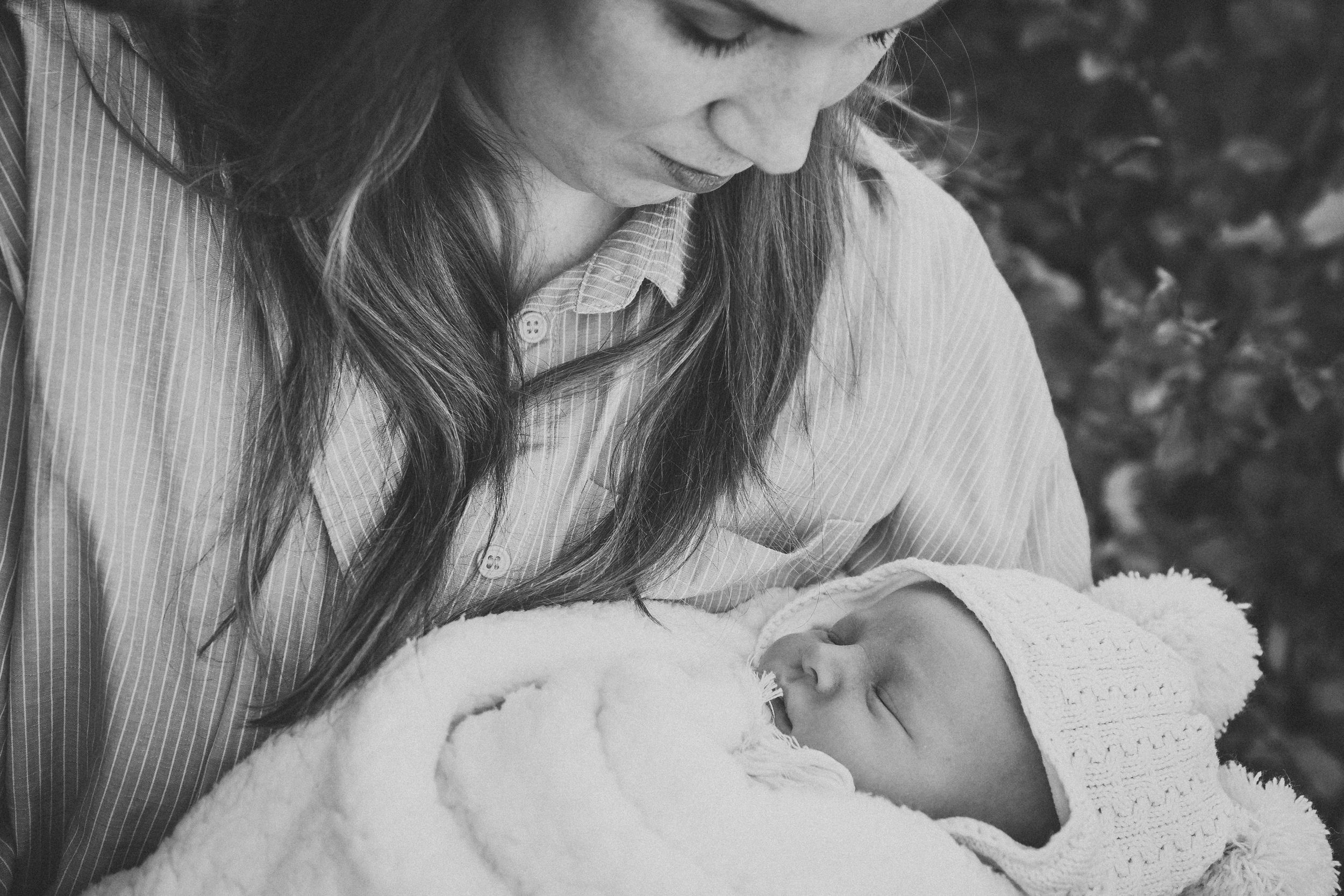 Intimate black and white portrait of tender moment between baby and caregiver.