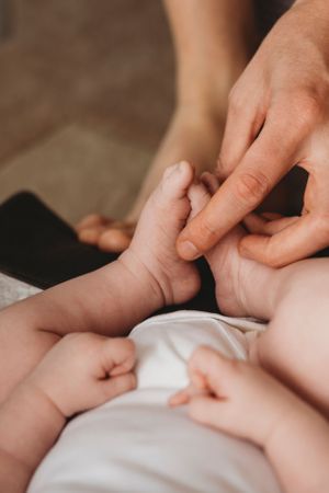 Close-up of tiny baby hands reaching for adult fingers against white fabric.