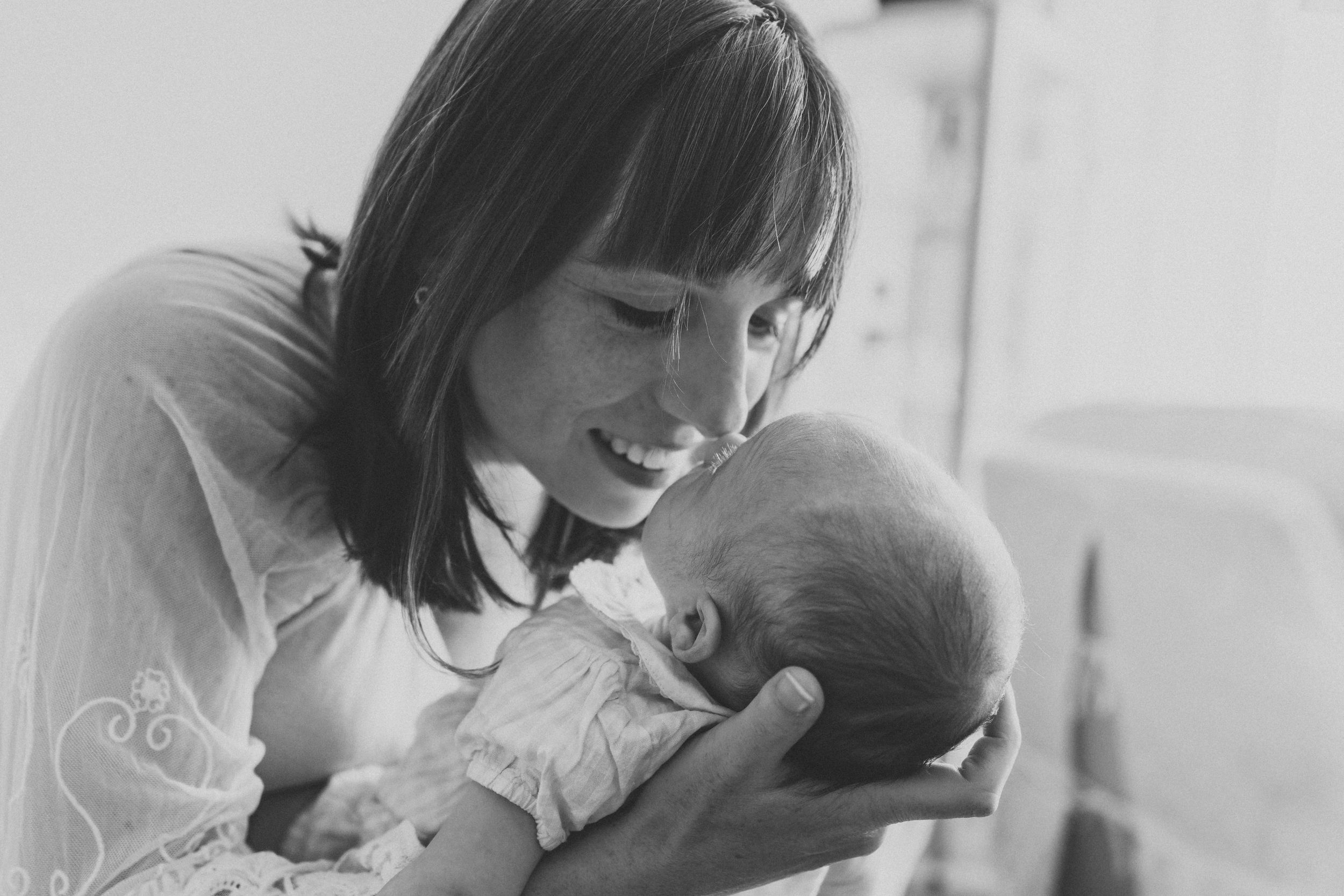 Black and white photograph of tender moment between parent and newborn.