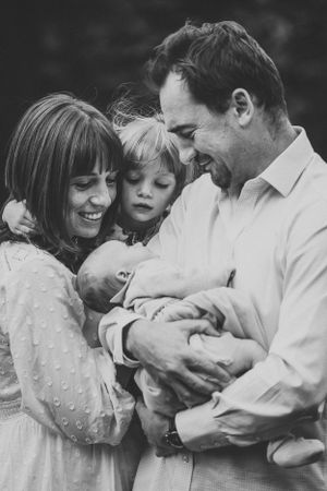 A heartwarming black and white family portrait showing tender moments with a newborn baby.