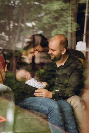 Tender family moment seen through window reflection with soft natural lighting.