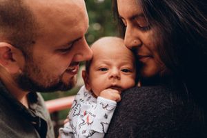Intimate family moment with baby in white patterned onesie.