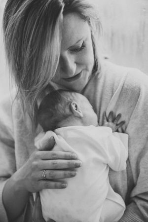 An intimate black and white portrait capturing a gentle moment with a newborn.