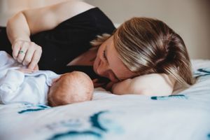 A peaceful moment of rest and bonding with a sleeping newborn on white bedding.