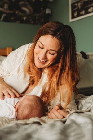 Tender moment between parent and infant captured in warm lighting on a bed.