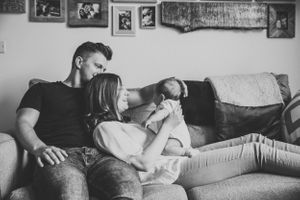 A relaxed family moment together on a couch with framed photos on the wall behind them.