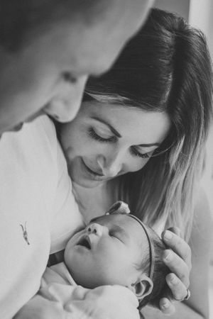 An intimate black and white portrait capturing a tender moment with a sleeping newborn.