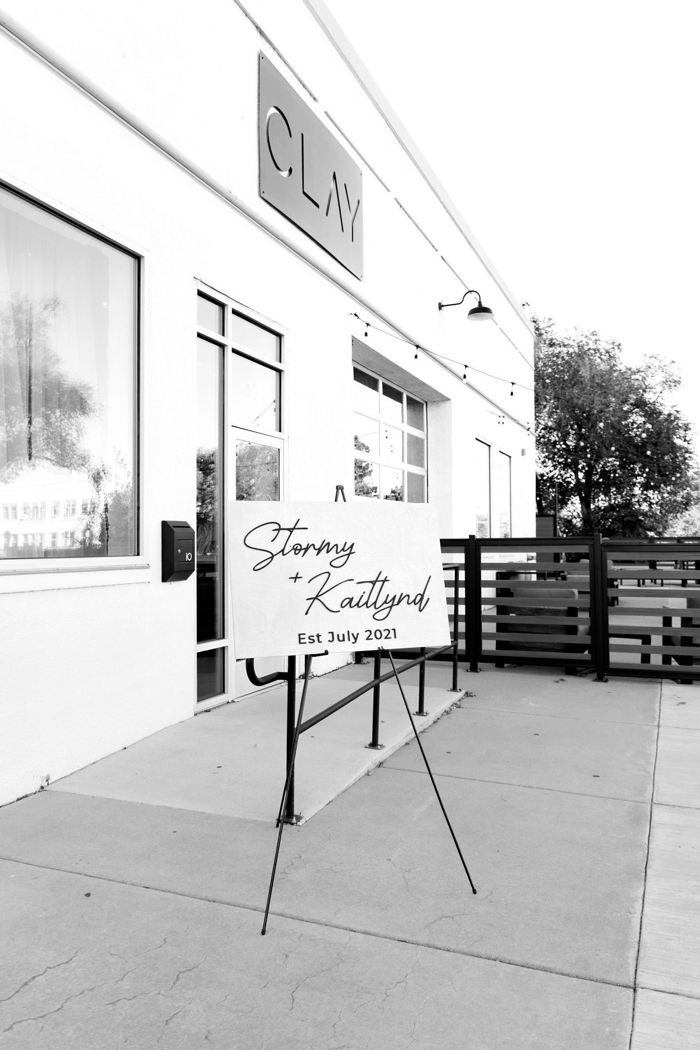 Black and white photo of a wedding welcome sign for Stormy and Kaitlynd, Est. July 2021, outside CLAY venue.
