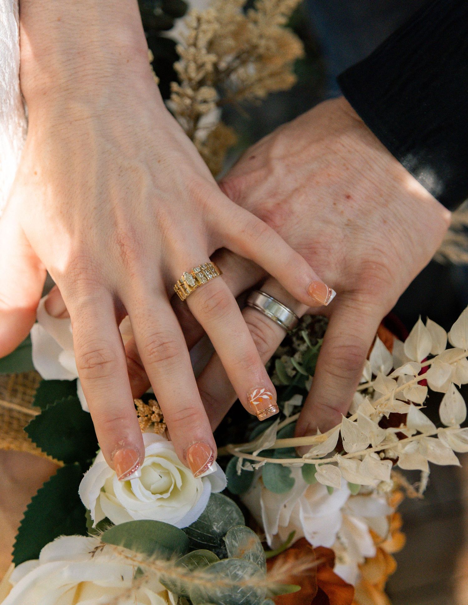 Elegant wedding bouquet with orange, white, and blue roses, eucalyptus greenery, and burlap ribbon on white chair.