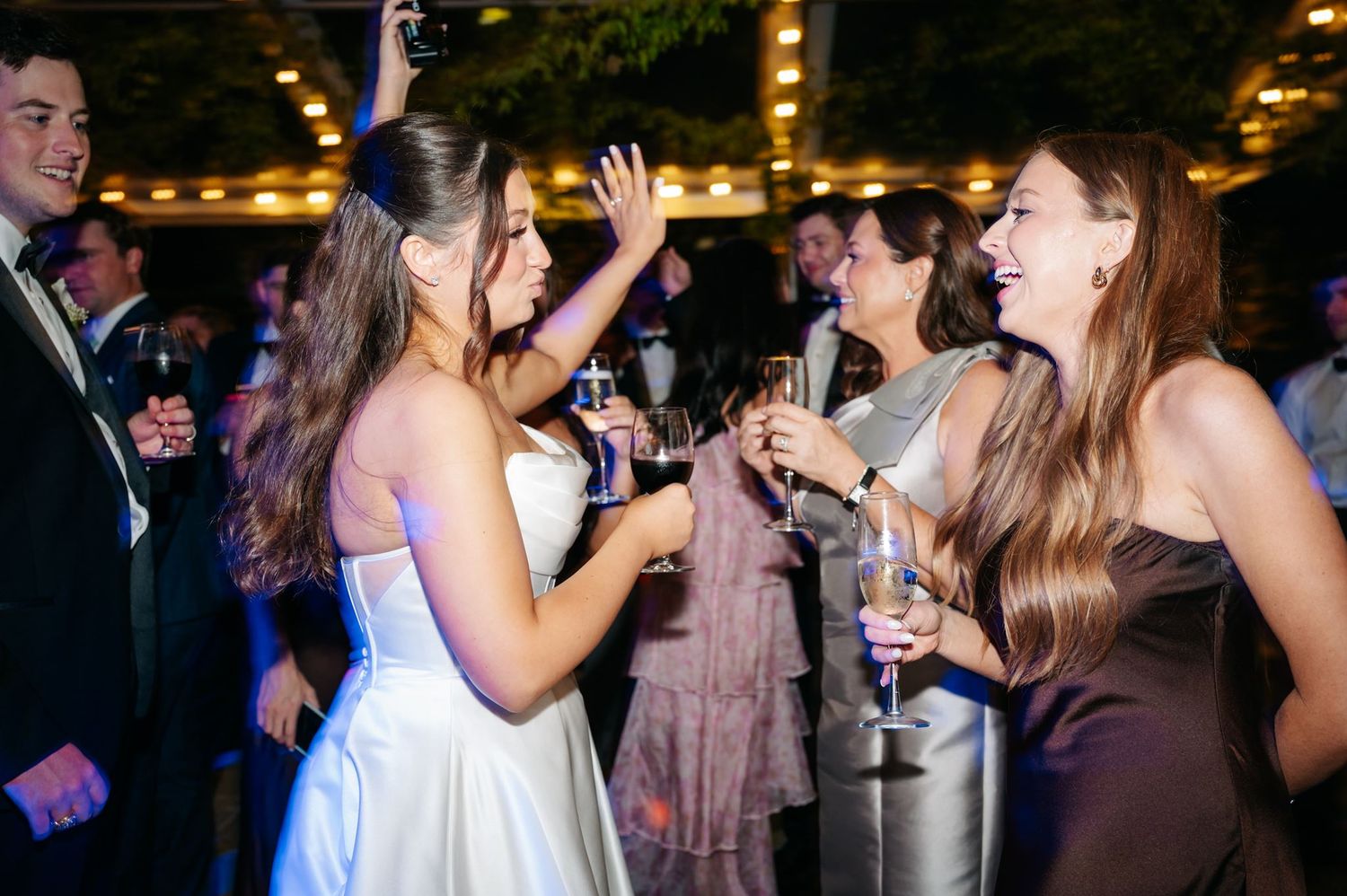 The bride dancing at wedding reception with champagne glass in her hand.
