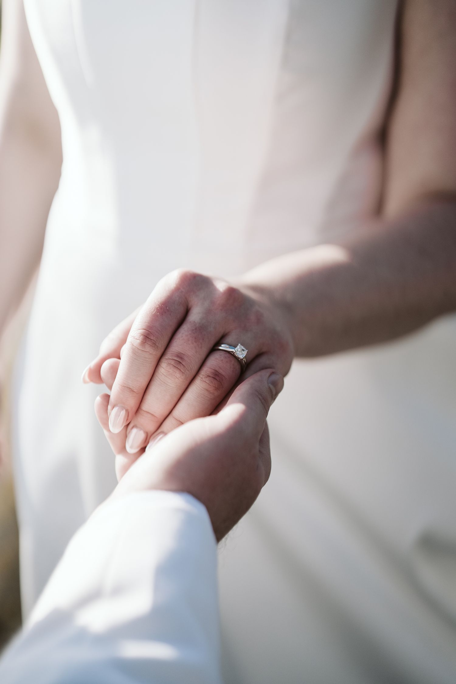 Bride and groom holding hands, close up of the wedding ring