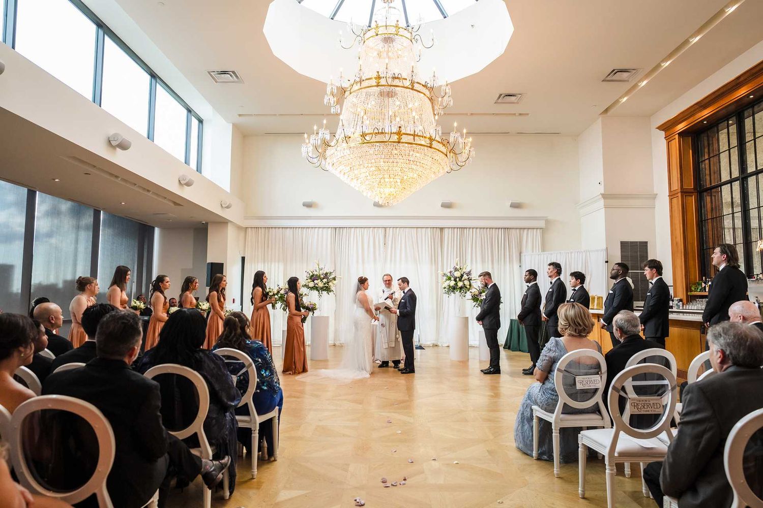 Elegant indoor wedding ceremony under a grand crystal chandelier in the view venue