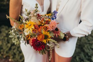 Colorful wildflower wedding bouquet with orange, blue and red blooms.