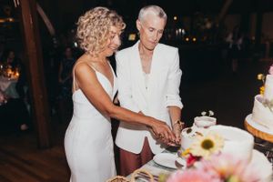 Wedding reception details showing cake cutting and table decorations in a dimly lit venue.