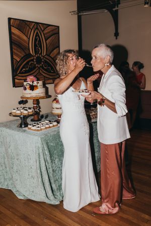 Wedding cake cutting ceremony at reception with mint green tablecloth and floral decorations.
