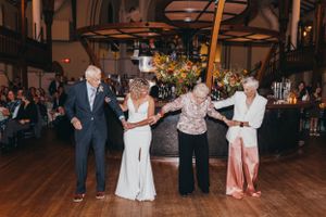 Guests dancing and celebrating at an evening wedding reception on wooden floors.