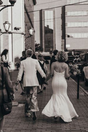 Black and white photo of wedding party walking on cobblestone street.