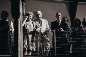 Wedding guests watching from a balcony in dramatic black and white lighting.