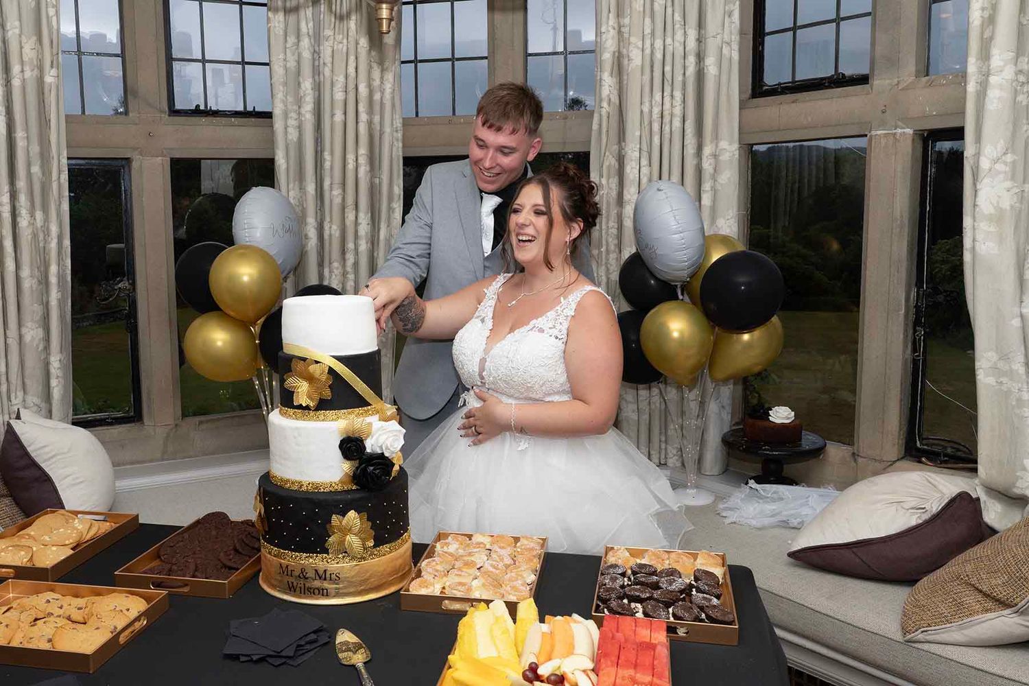 Bride and groom cutting a elegant black and gold wedding cake at their reception.