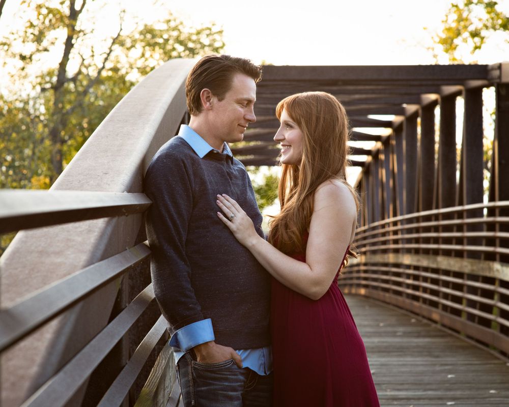 Couple sharing a romantic moment on a wooden bridge at sunset.