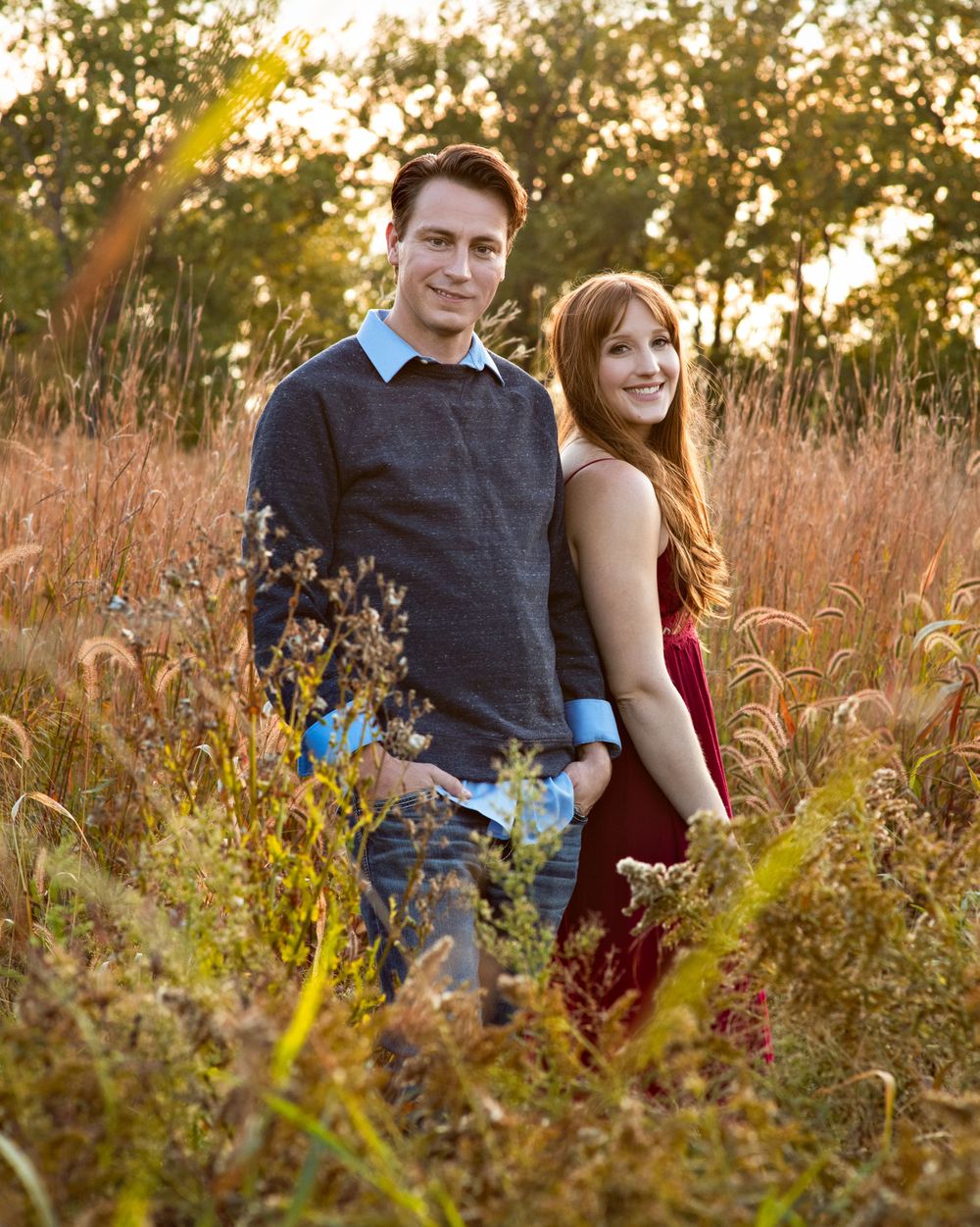 Couple posing together in a golden autumn meadow at sunset.