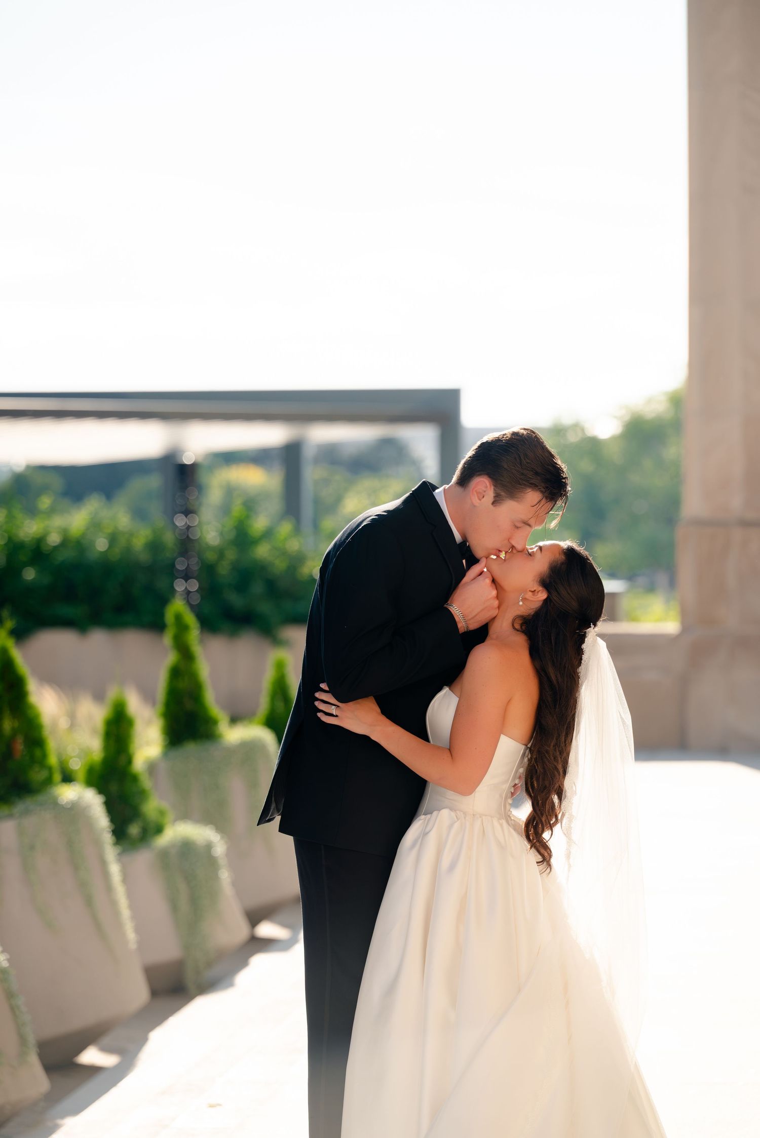 Couple embracing on a beach with a rainbow over lake michigan chicago, bride in white gown and groom in black suit.